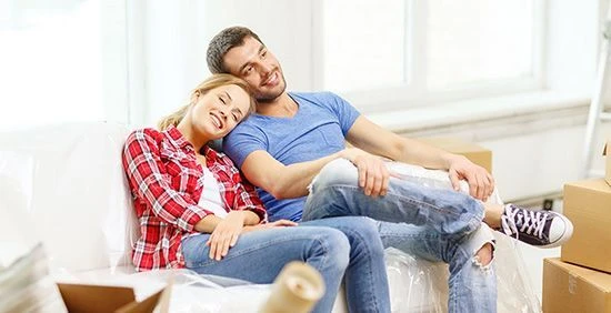 A couple relaxing amidst moving boxes, appearing content and happy in a new home.